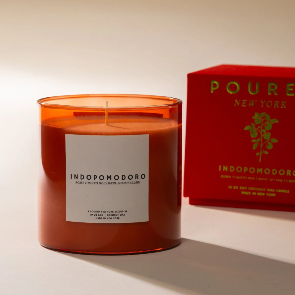 Orange candle with a label next to a red box on a white background