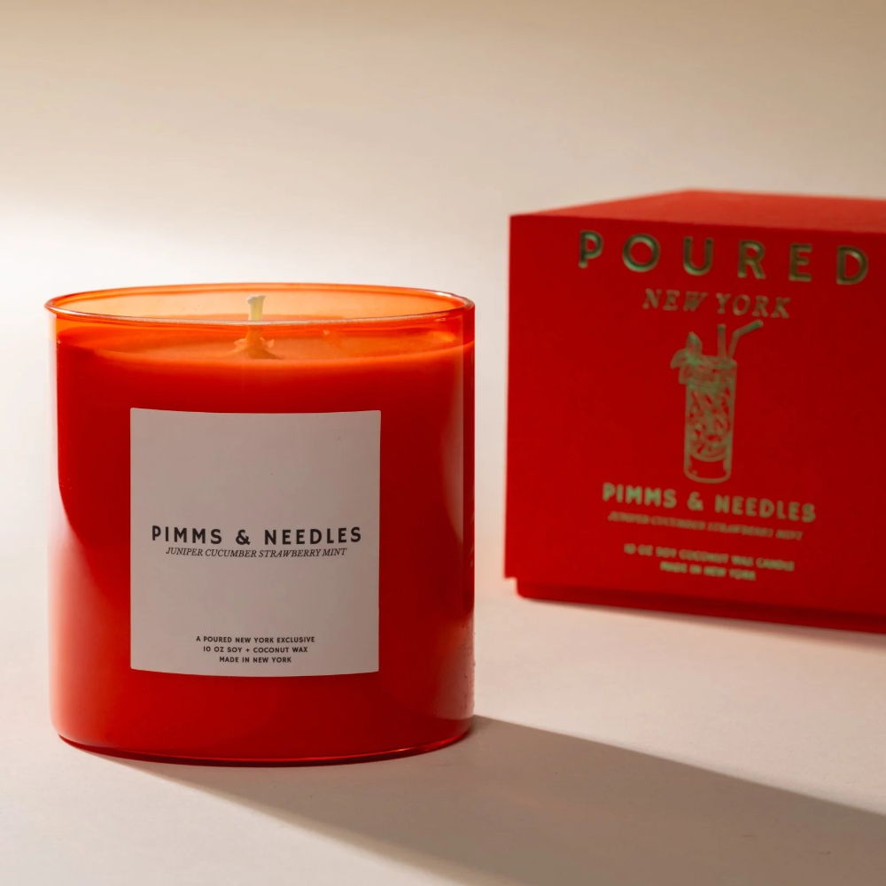 Red candle with a white label and matching box on a light background