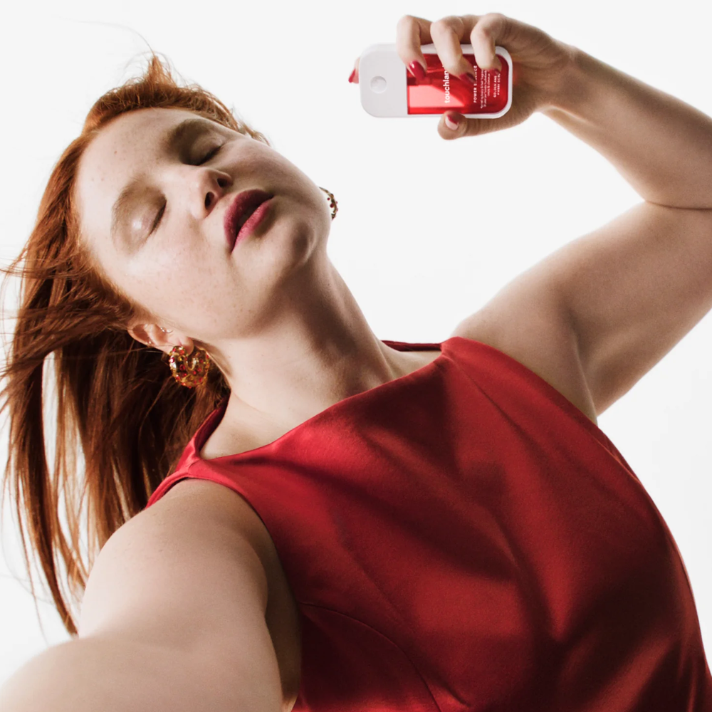 Woman in a red dress holding spray bottle against a white background