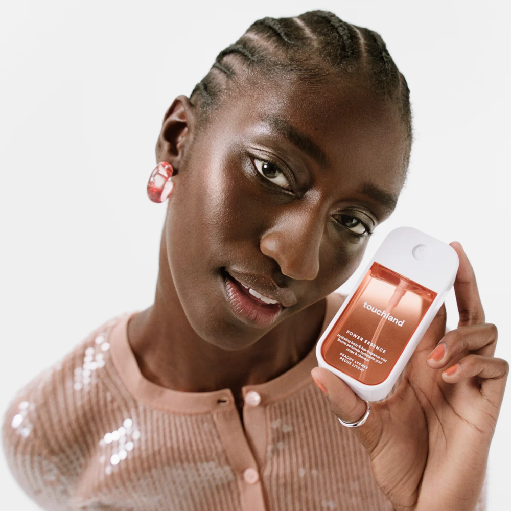 Woman holding a skincare product with a visible brand name on a plain background