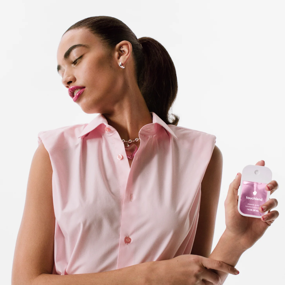 Woman holding Touchland product against a white background