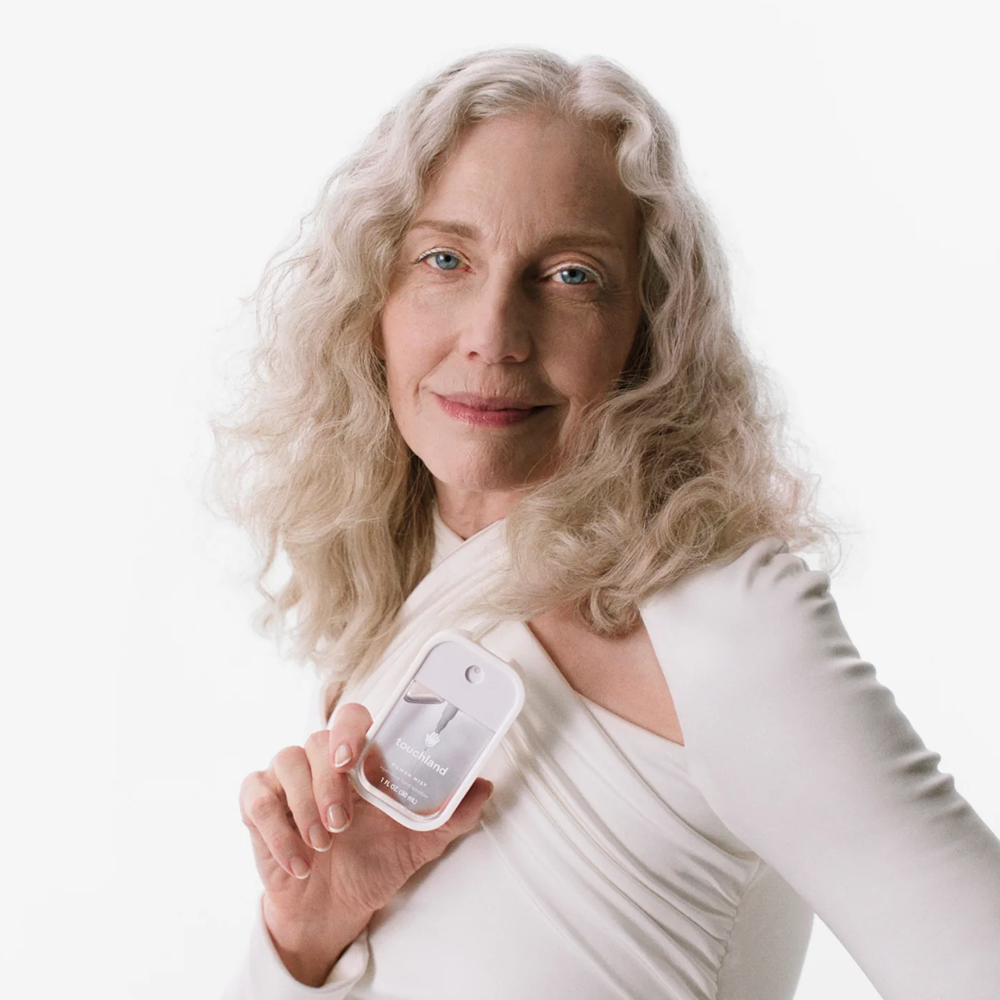 Woman holding Touchland product against a white background