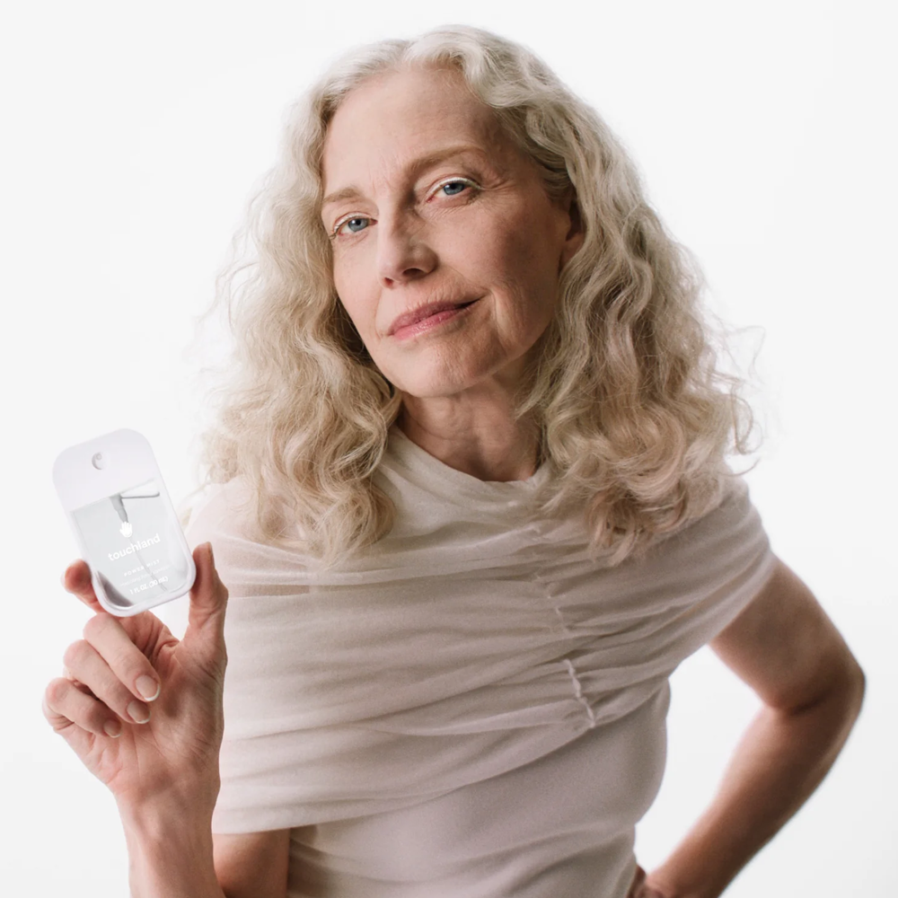 Woman holding Touchland product against a white background