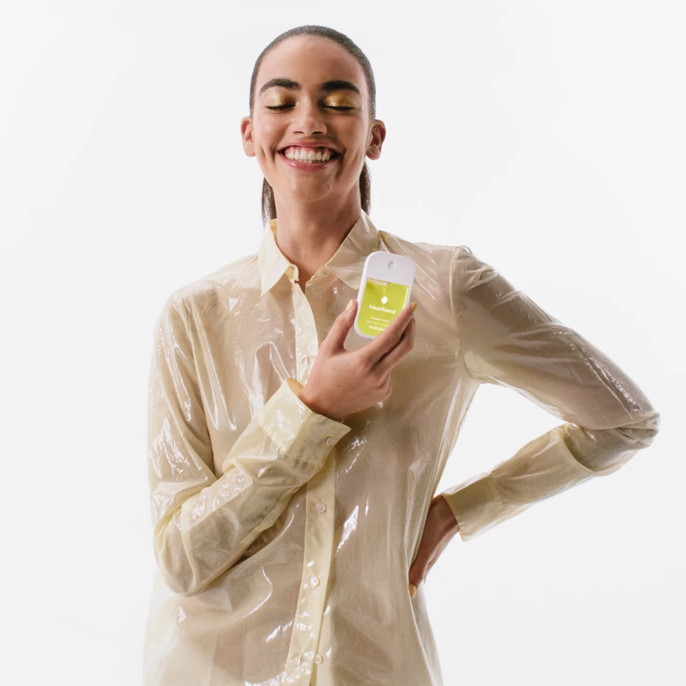 Woman holding Touchland product with a plastic shirt on a white background