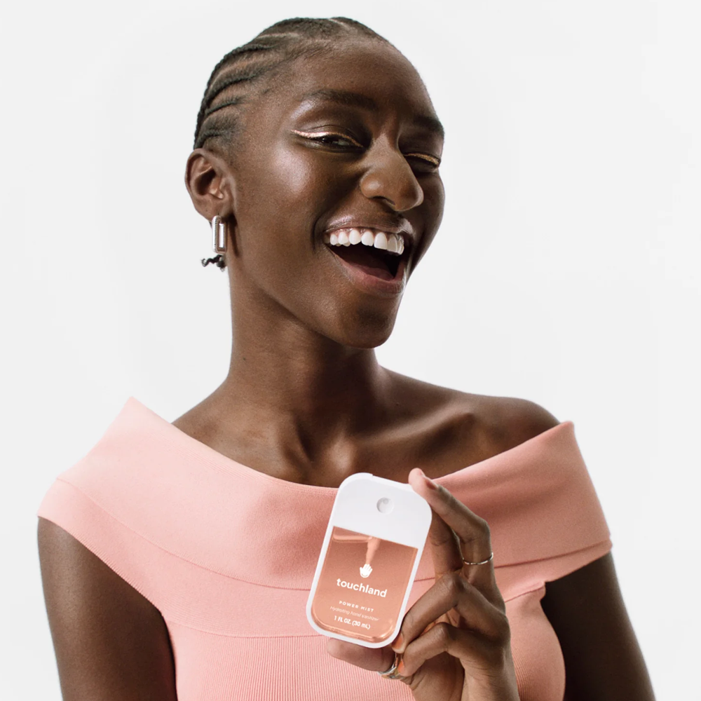Woman holding a product with 'Touchland' branding against a plain white background