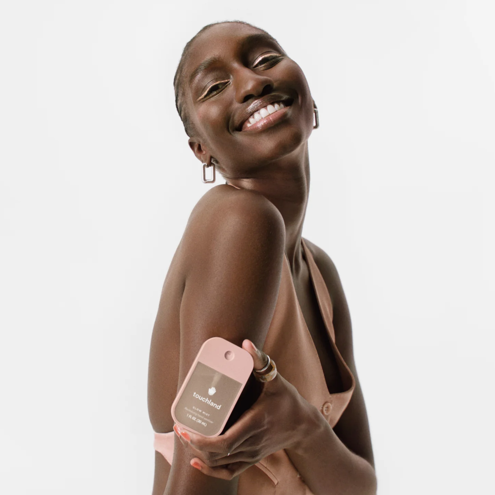 Woman holding pink Touchland product with a white background