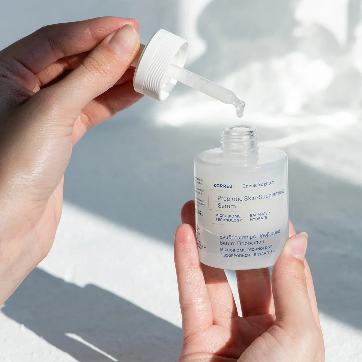 Hand holding a dropper bottle of KORRES Probiotic Skin Supplemen Serum against a light background