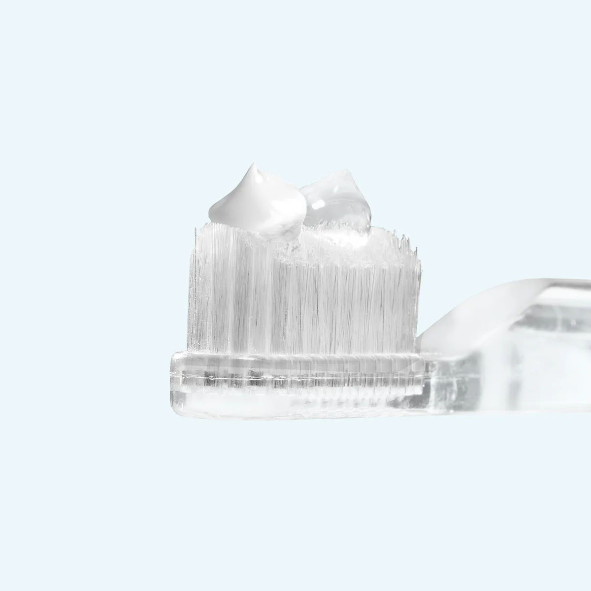 Supersmile Toothpaste and Accelerator droplets on a toothbrush in front of a light background. 