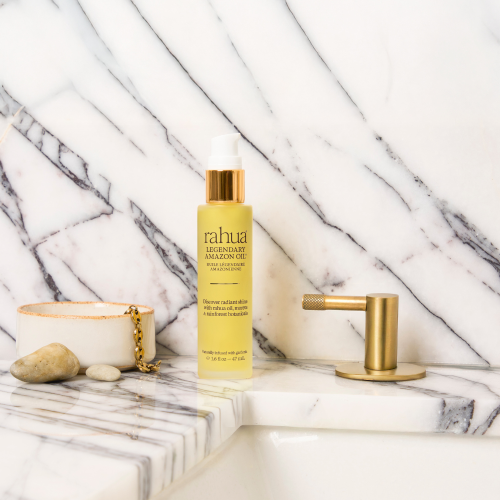 Bottle of Rahua Legendary Amazon Oil on a marble surface with a marble background