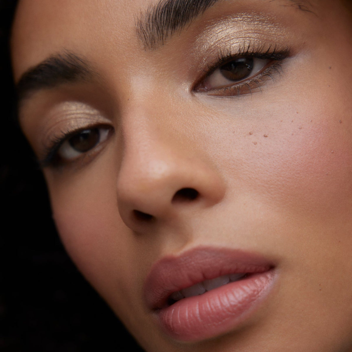 Closeup of woman's face wearing Wonderblush makeup products. 