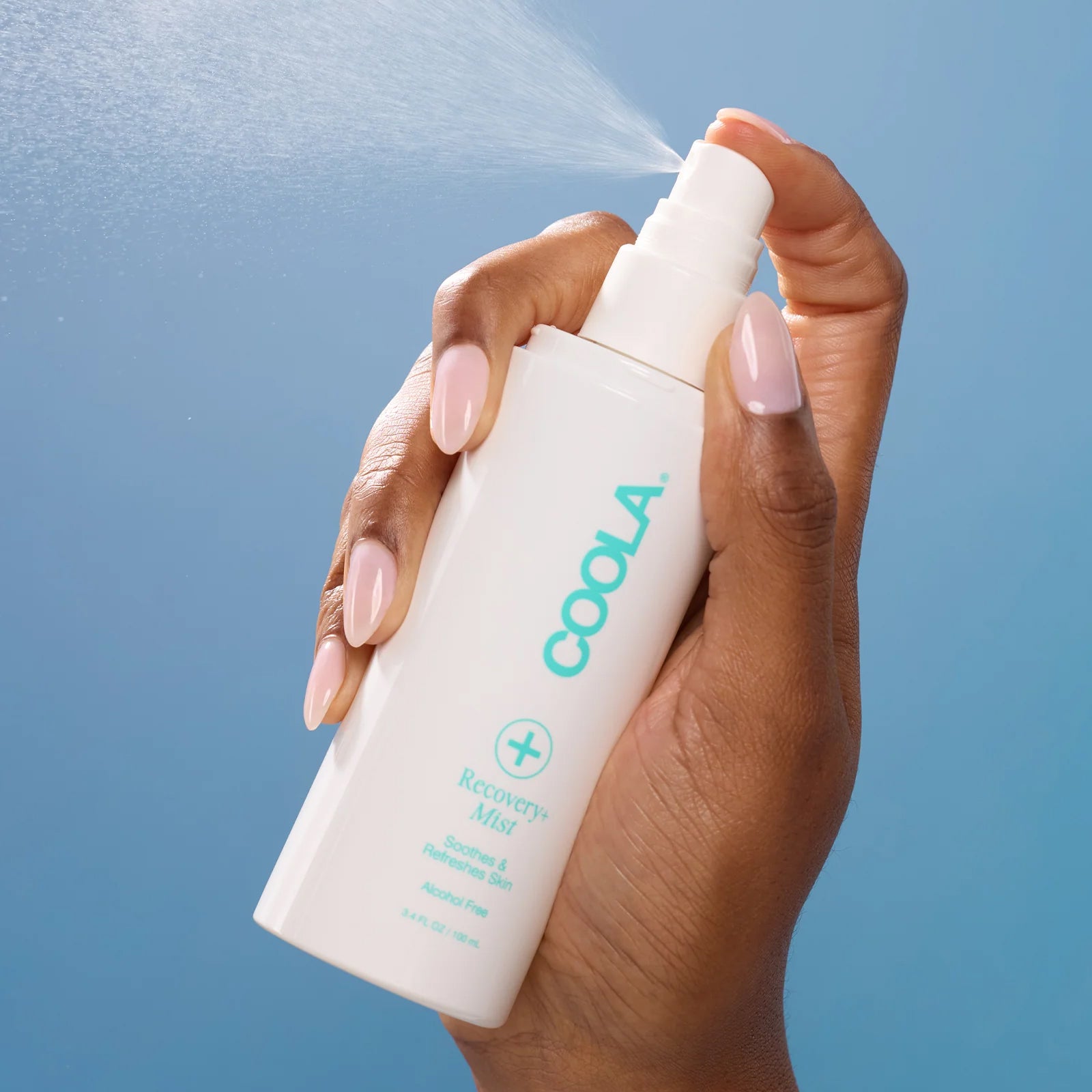 Hand spraying COOLA Recovery+ Mist product