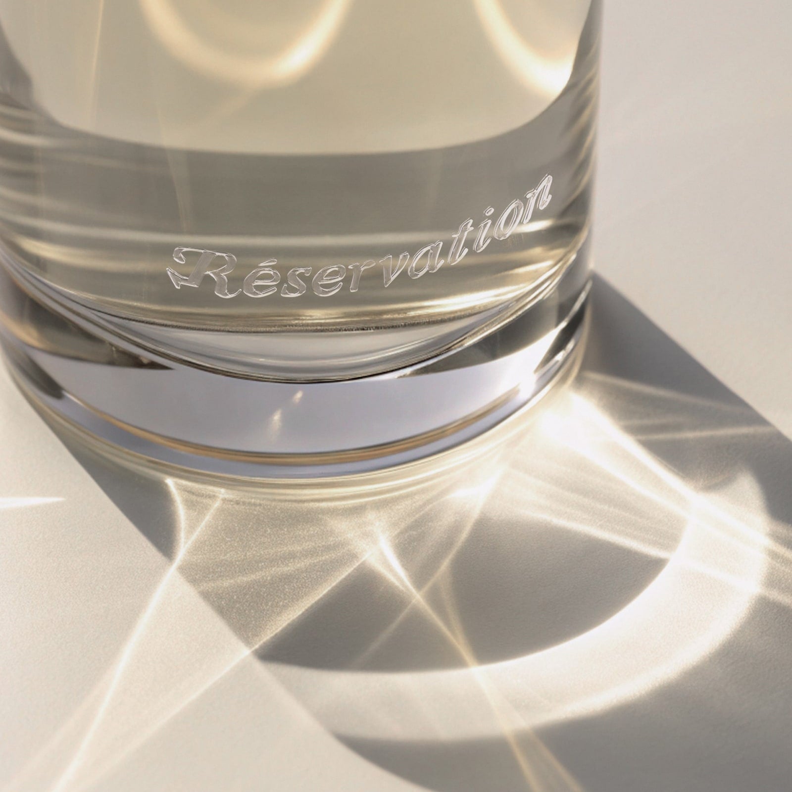 Light reflecting off of a perfume bottle with 'Réservation' branding.