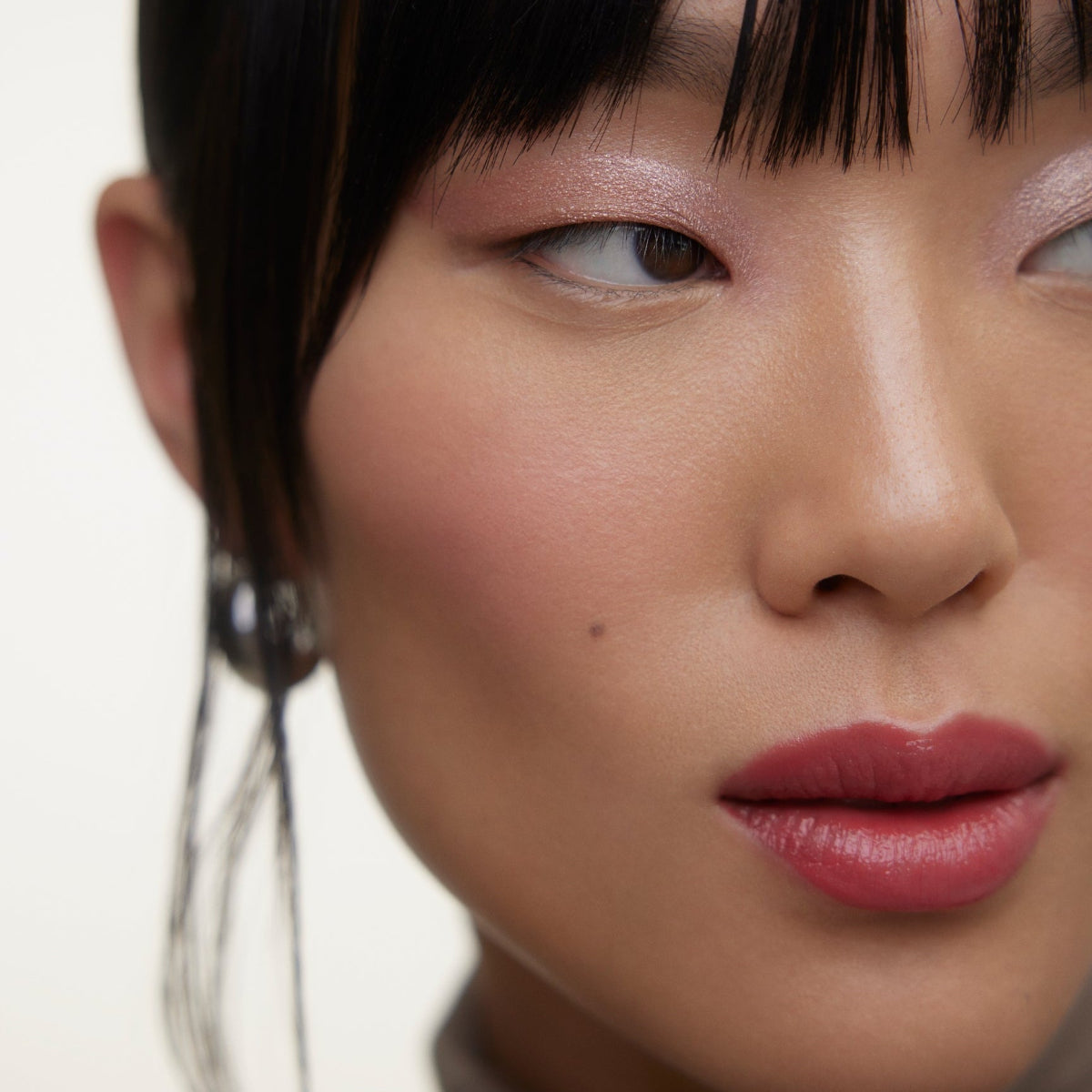 Closeup of woman's face wearing Wonderblush makeup products. 