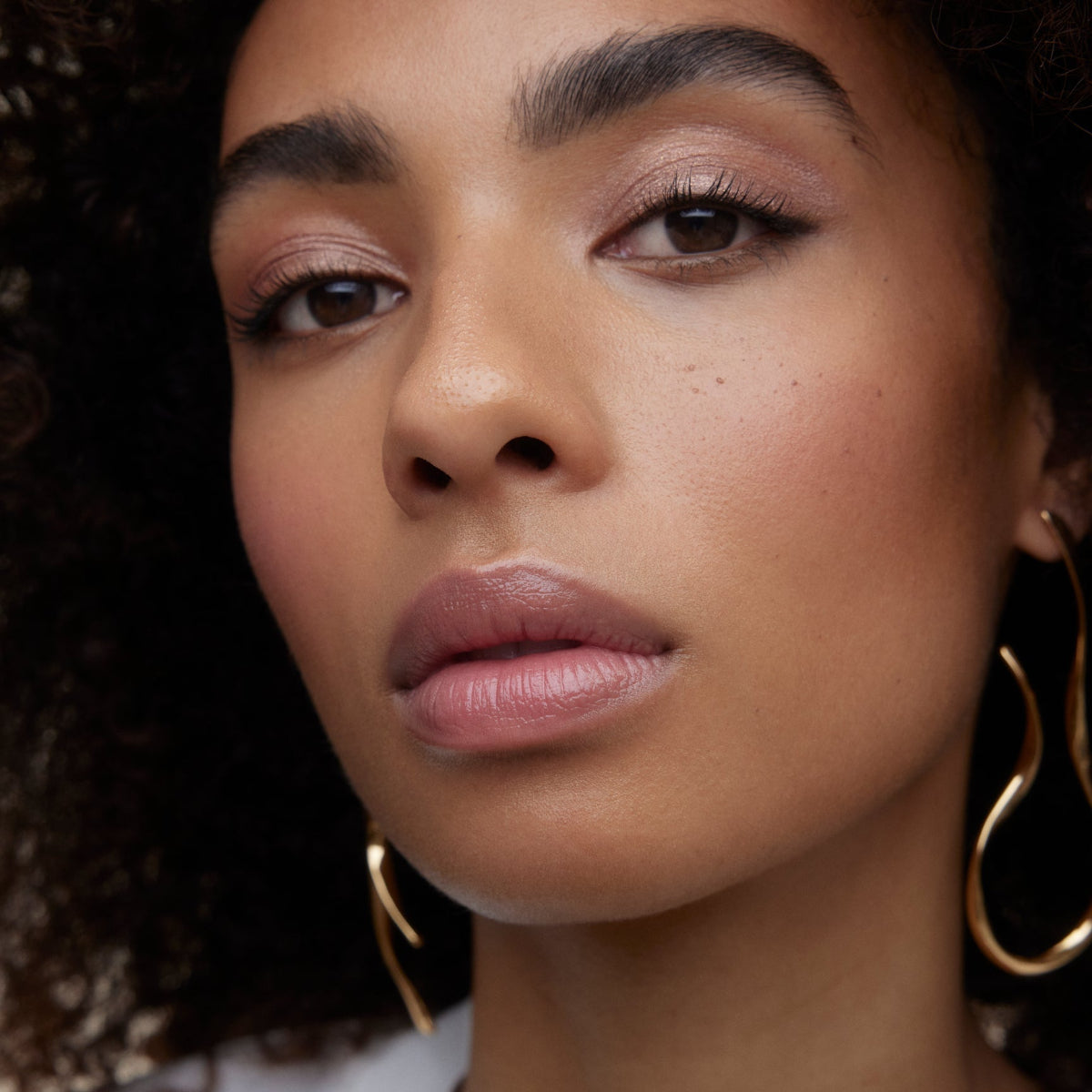 Closeup of woman's face wearing Wonderblush makeup products. 