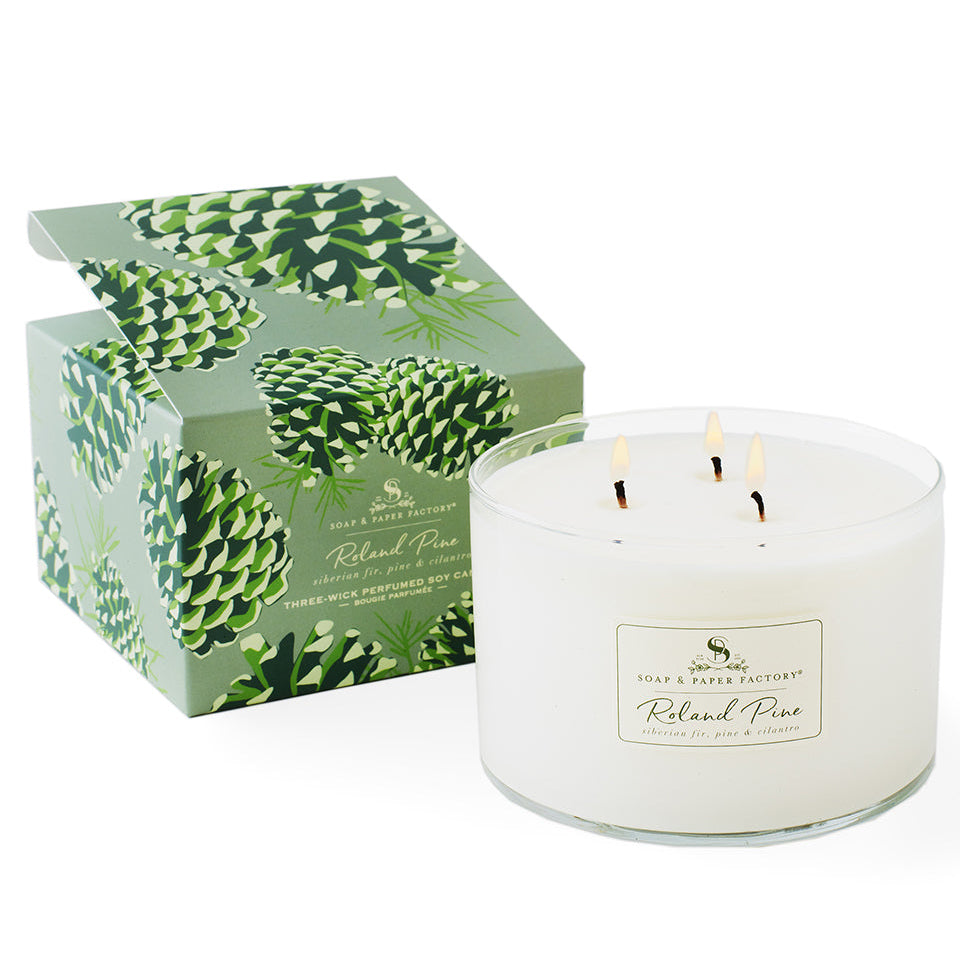White candle with a green packaging box featuring pine cone design on a white background