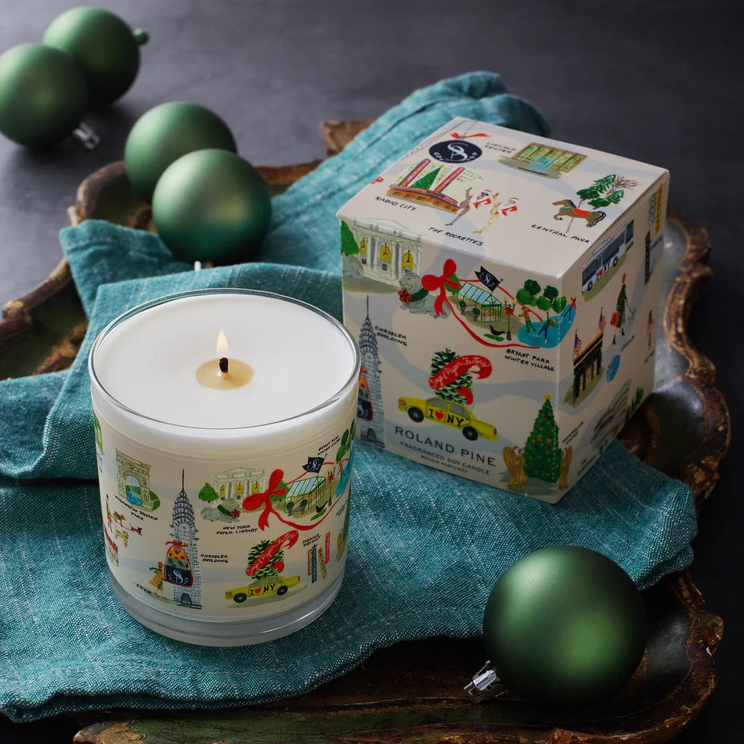 Roland Pine Candle with decorative packaging and green ornaments on a dark surface