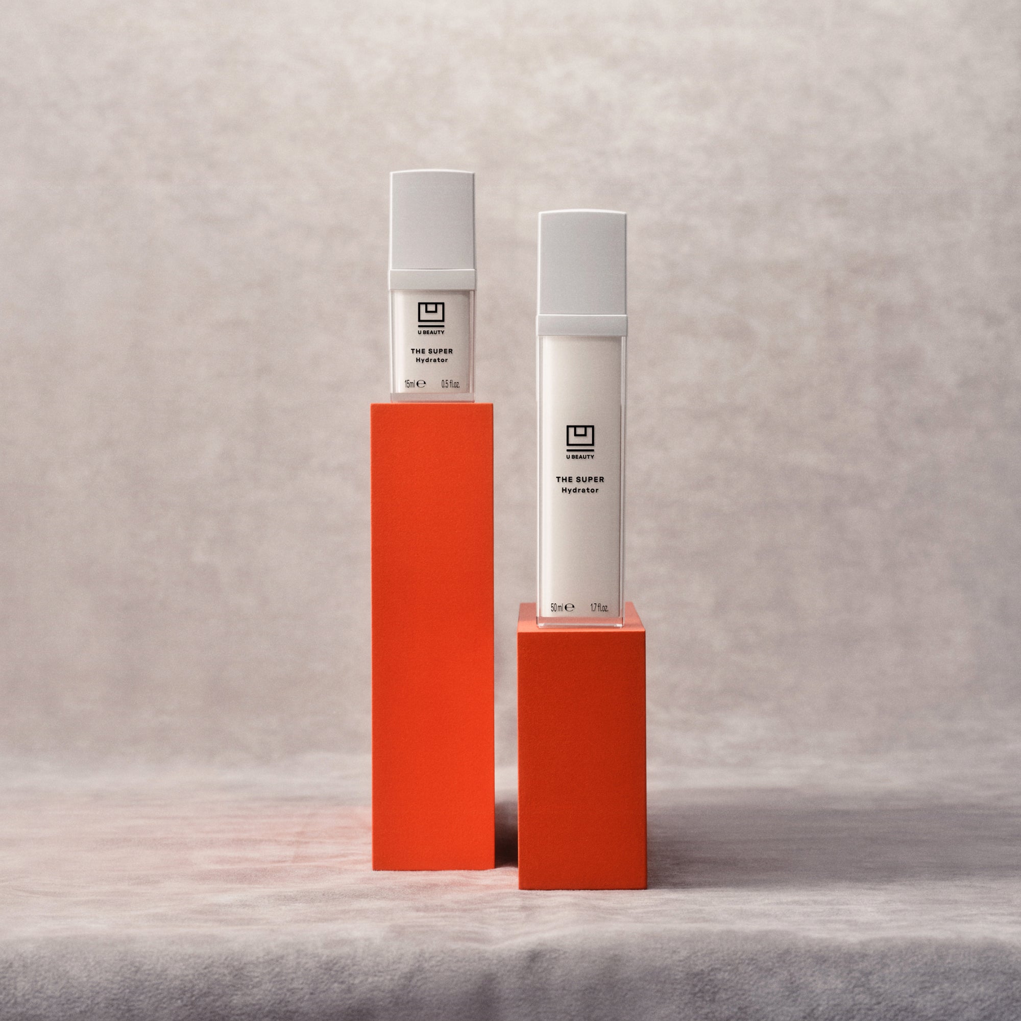 U Beauty's The SUPER Hydrator in two sizes on red pedestals.