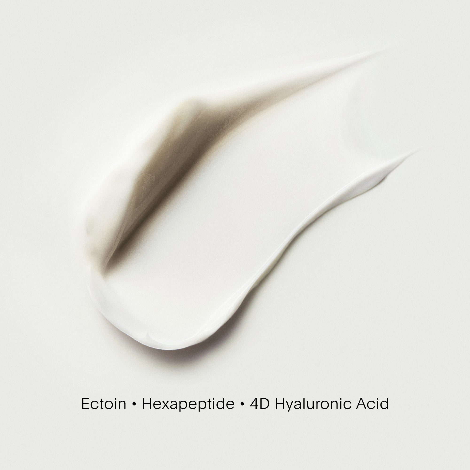 Close-up of a smooth, white cream with text indicating ingredients on a light background