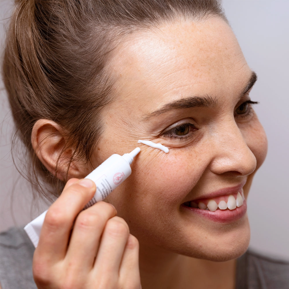 Woman applying SVR Palpebral eye cream under her eye with a applicator.