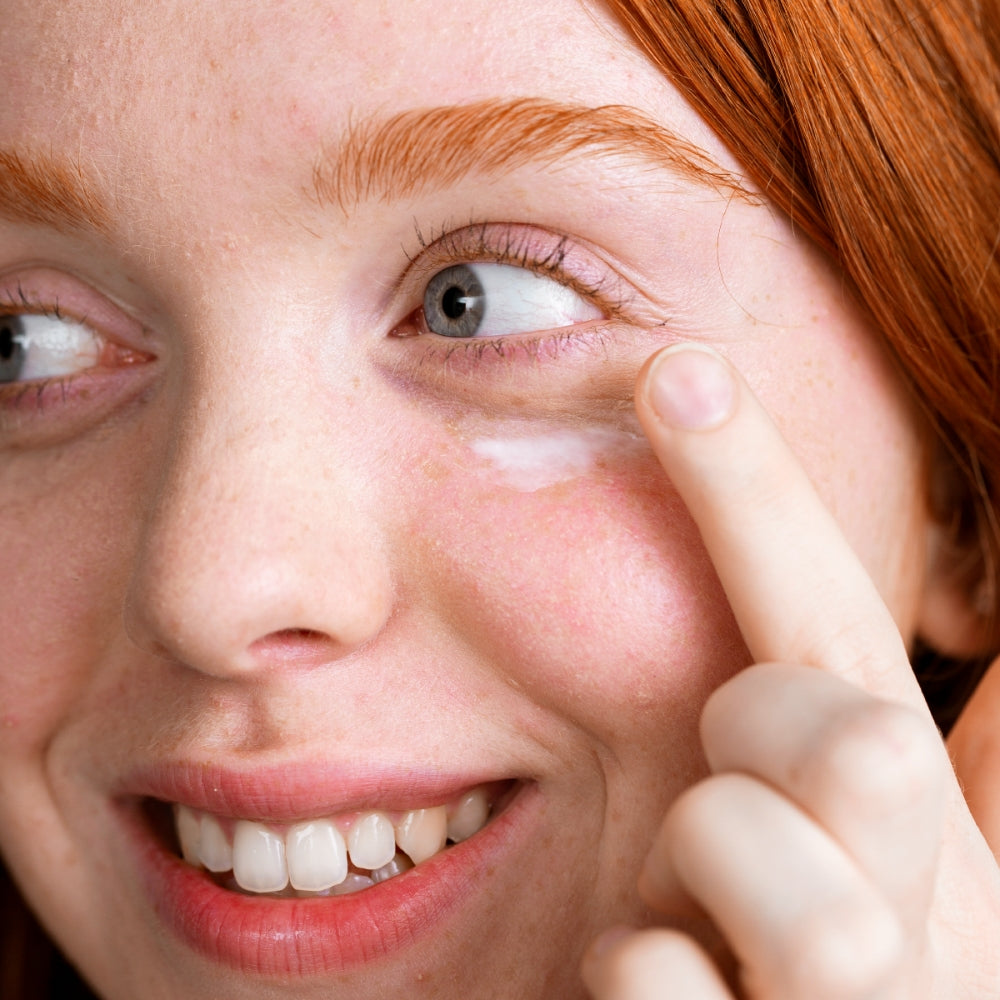 Close-up of a person applying Palpebral Eye cream to their face with a finger.