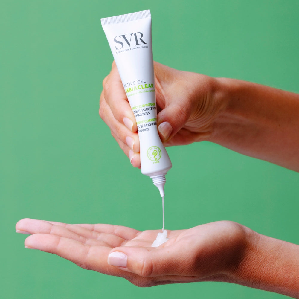 Hand holding a tube of SVR Sebiaclear Active gel with green background