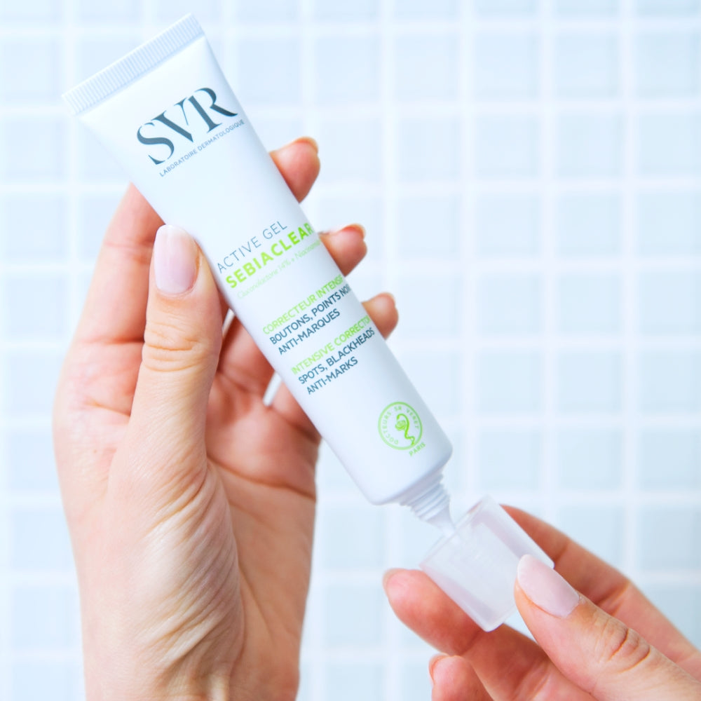 Hand holding a SVR  Sebiaclear Active Gel  product against a light blue background