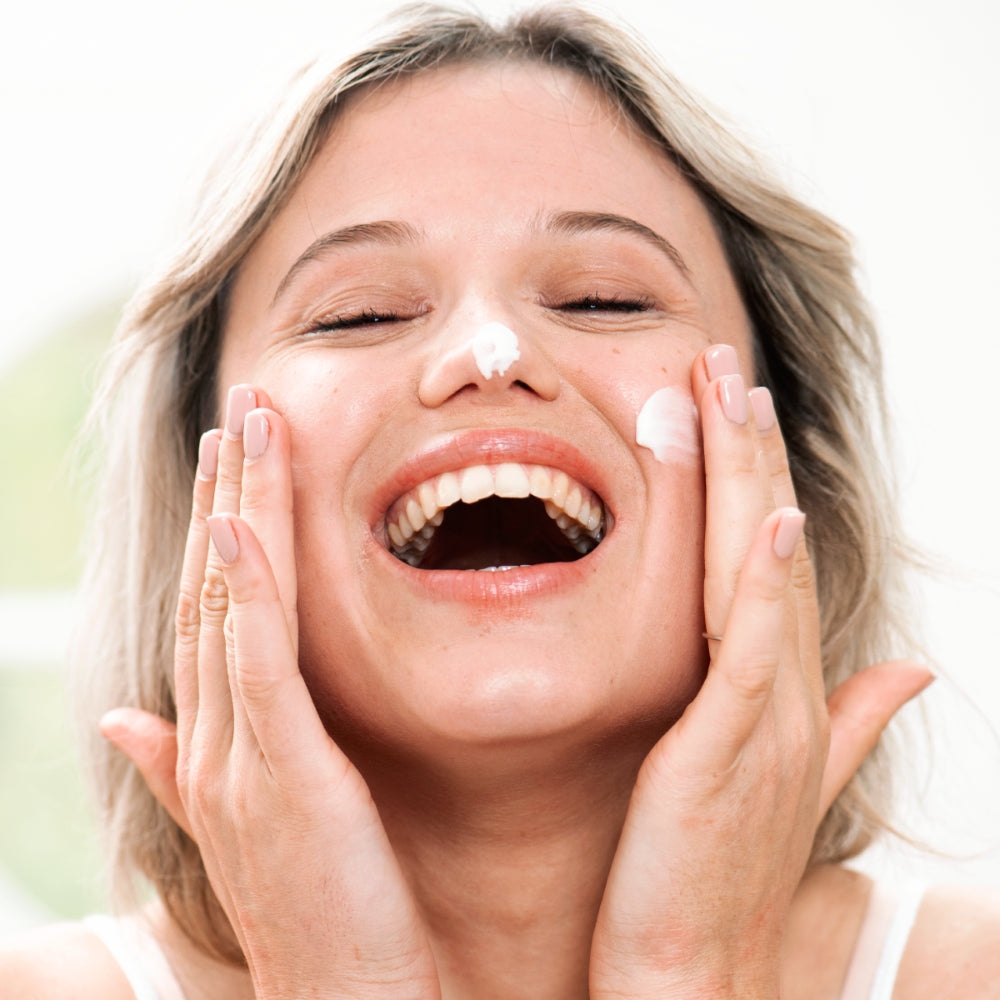 Woman applying Sensifine hydracream to her face with a blurred background
