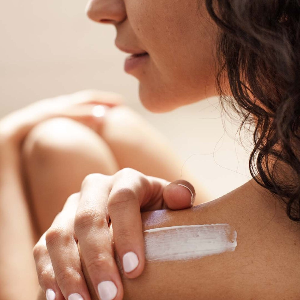 Woman applying SVR Topialyse cream to her shoulder