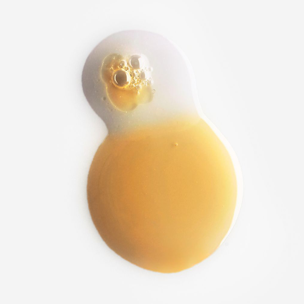 A droplet of golden yellow liquid with a frosted white top section and small bubbles, shown on a plain white background.