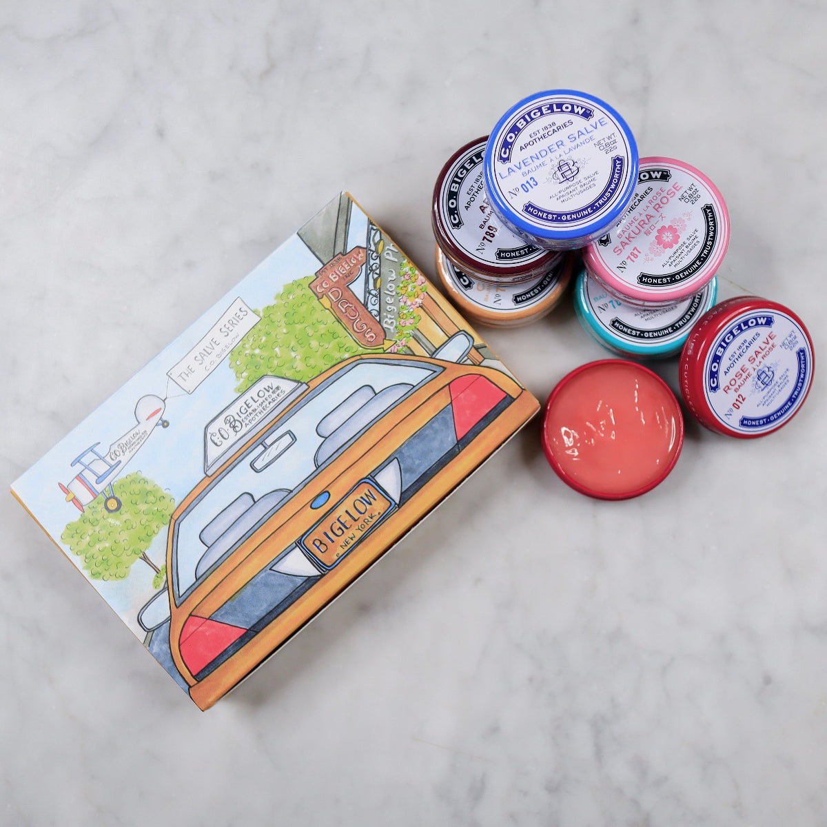 Set of small containers with lids and a colorful box on a light gray surface