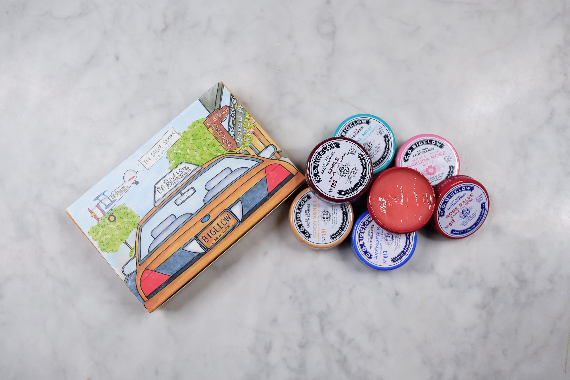 Collection of small containers with lids and a colorful box on a light gray background