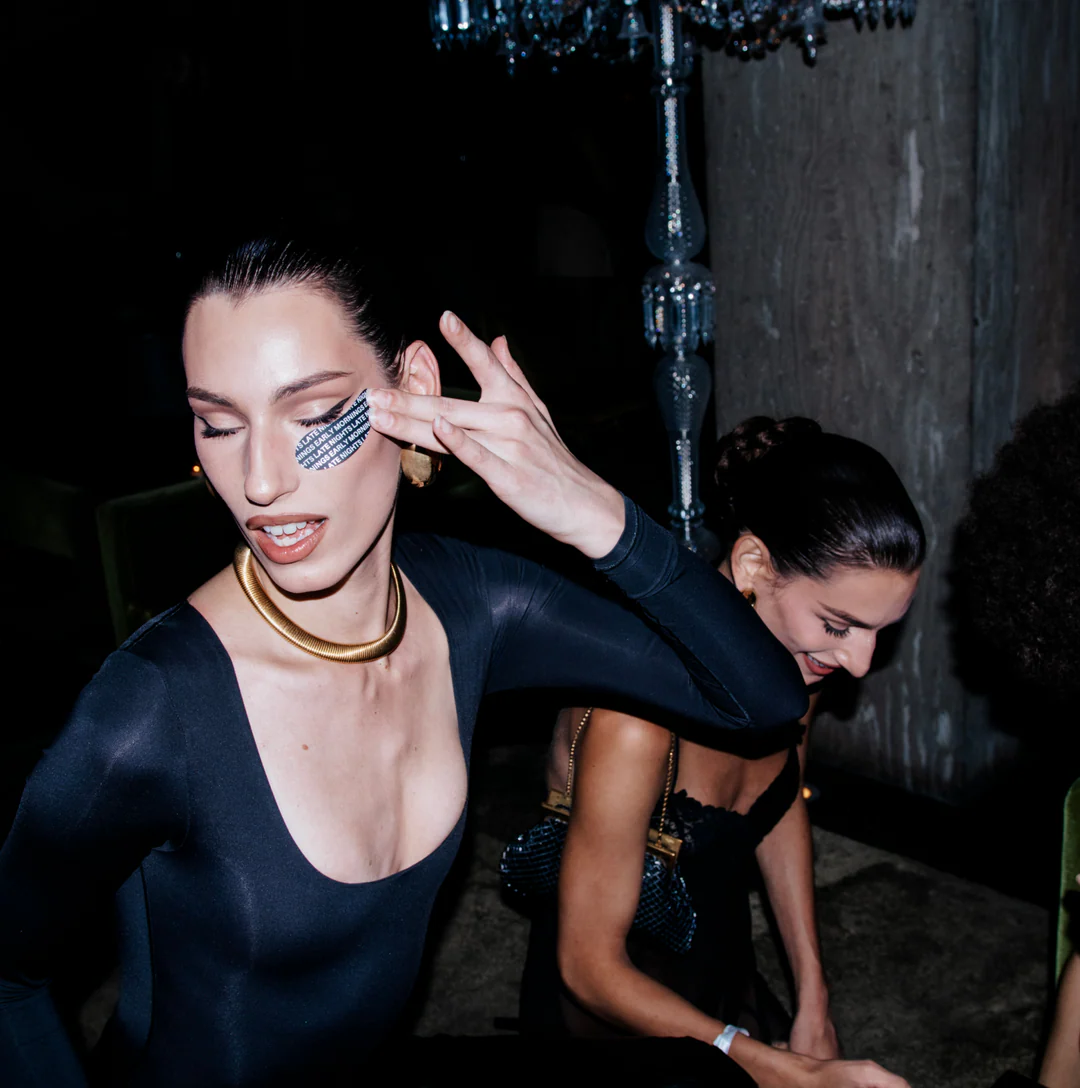 Two women in formal attire at a party with a dark background