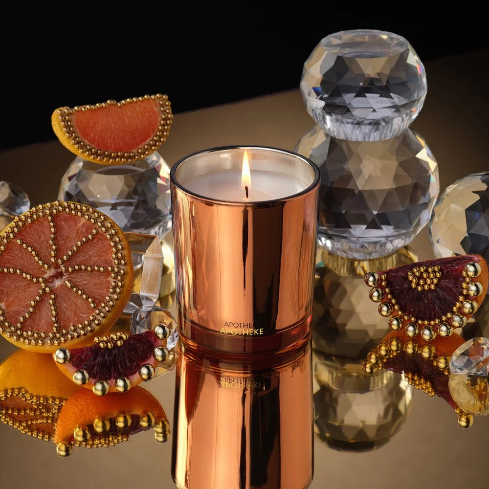Rose gold candle with decorative elements on a reflective surface