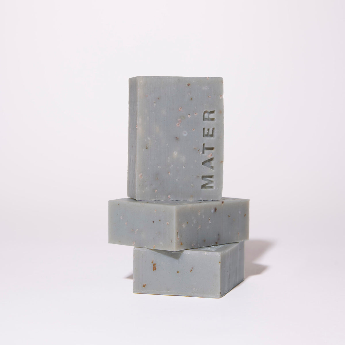 Three stacked rectangular bars of gray speckled soap with the brand name 'MATER' embossed vertically on the top bar, set against a clean white background.