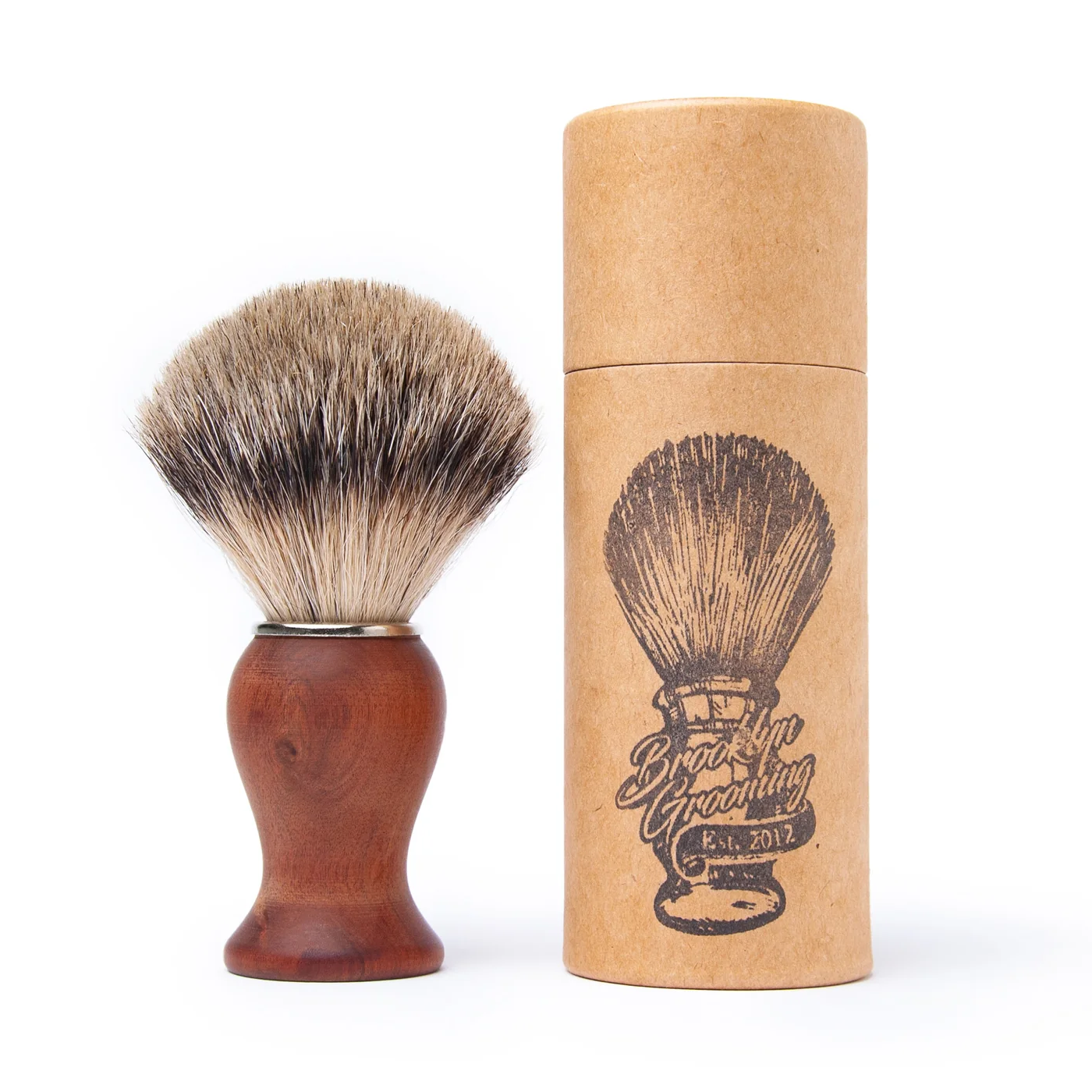 Shaving brush with brown handle and bristles next to a cardboard tube packaging on a white background