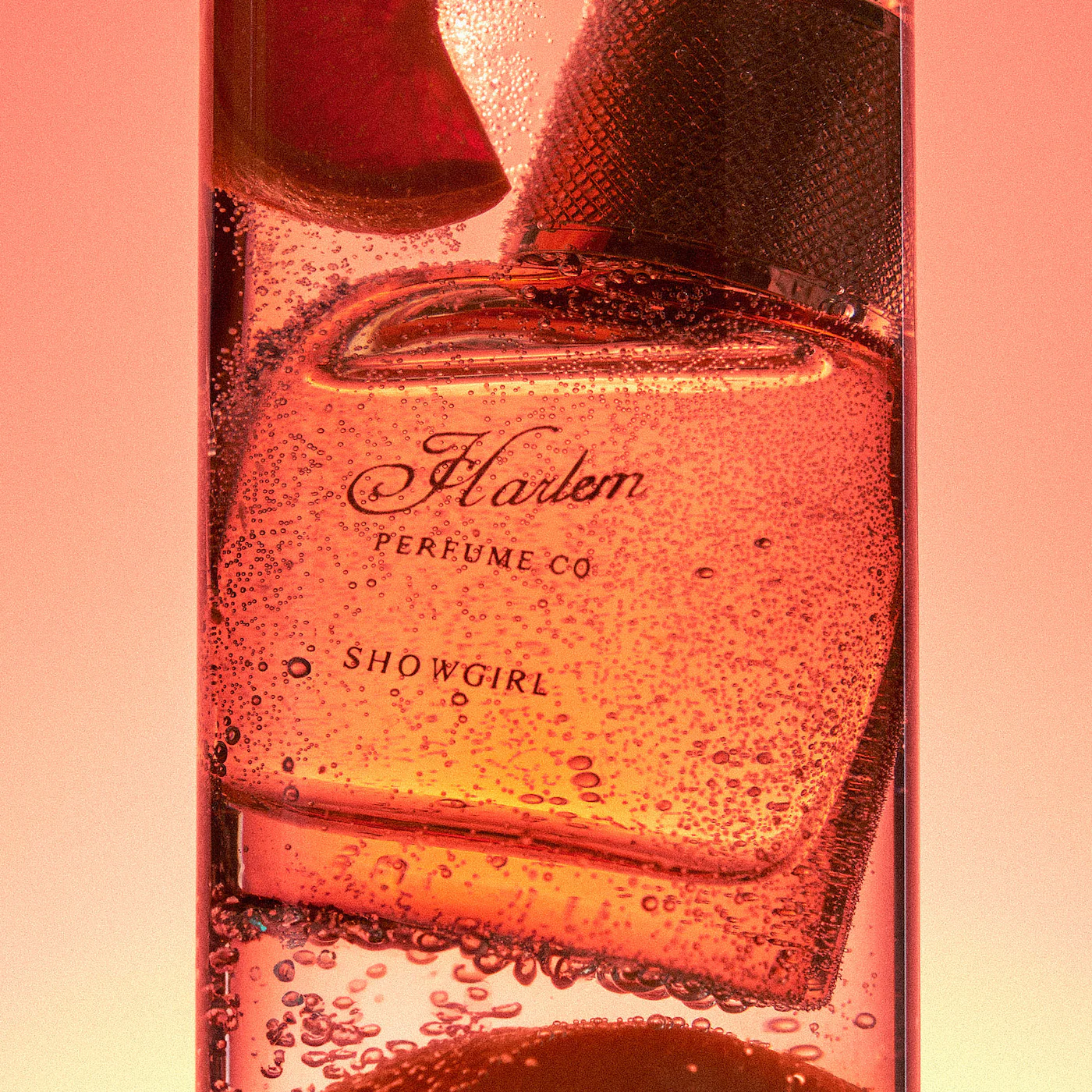 Perfume bottle labeled 'Harlem Perfume Co Showgirl' with a red and pink gradient background.