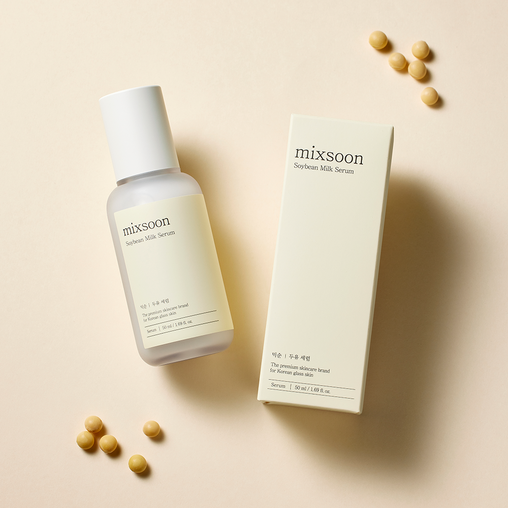 A bottle of mixsoon Soybean Milk Serum and its matching cream-colored box, styled on a warm beige background with scattered soybeans.