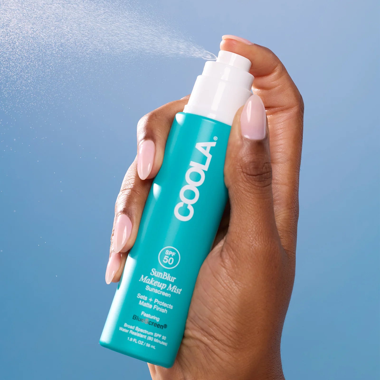 Hand spraying COOLA SunBlur Makeup Mist product