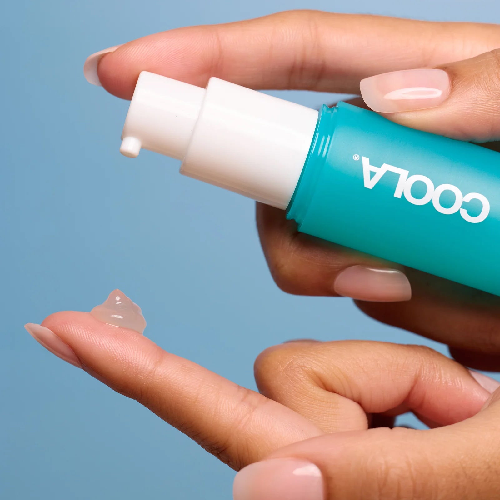 Hands expelling Coola SunBlur Primer product onto finger