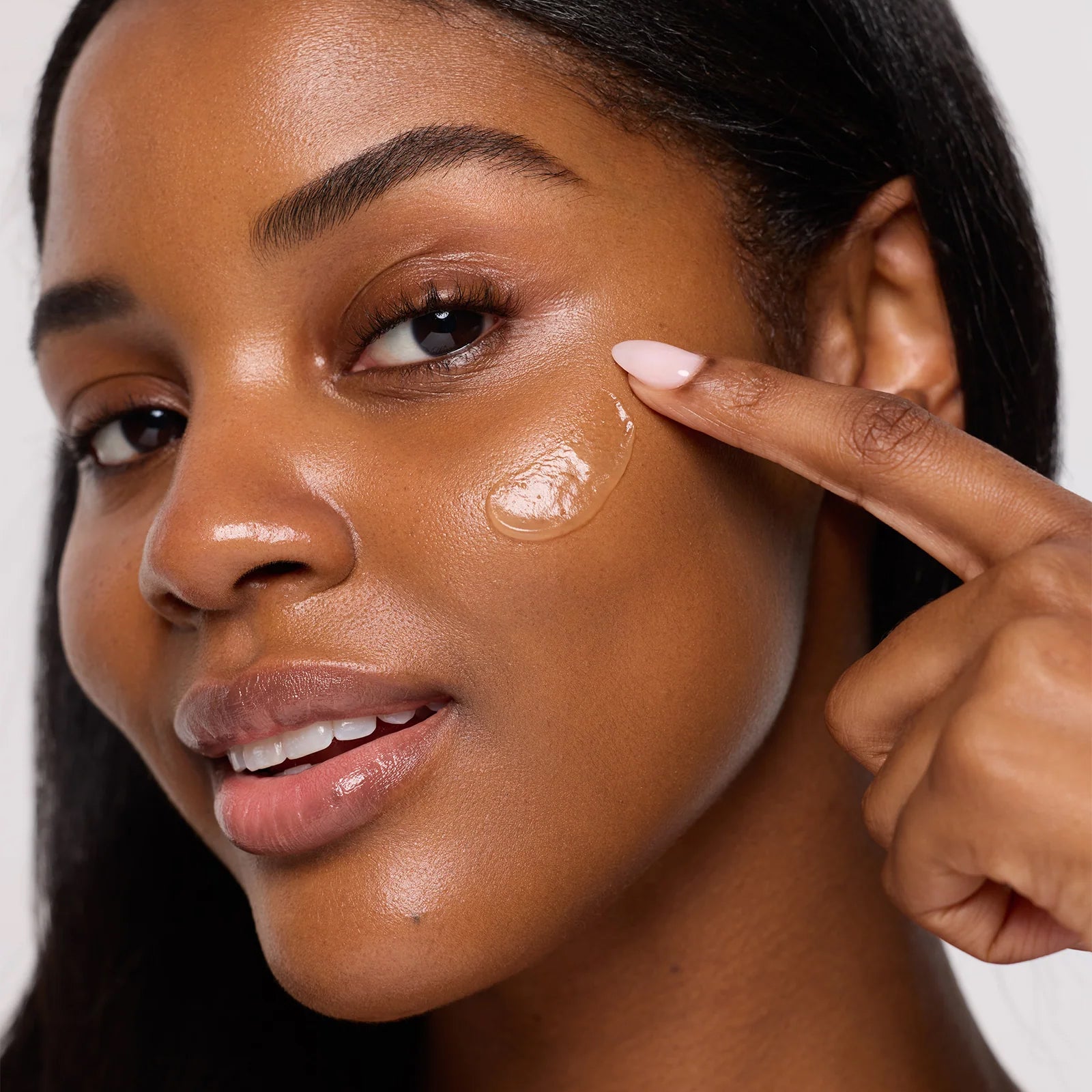 Woman applying Coola SunBlur Primer product to her cheek