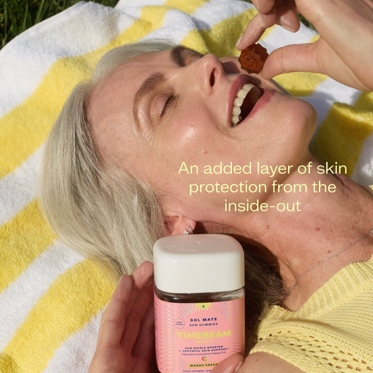 Person laying on a yellow and white, striped towel eating a Timebeam Beauty - Sol Mate Supplement Gummy with text about skin protection.