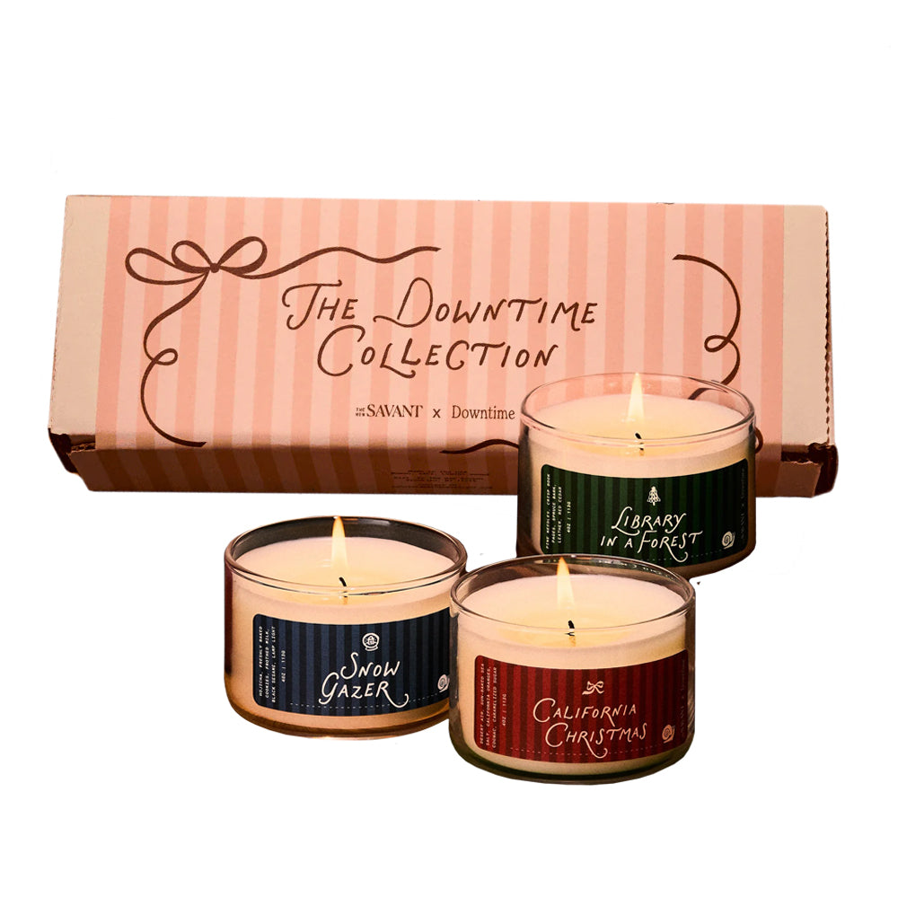 Three scented candles with labels in front of a box labeled 'The Downtime Collection' on a white background.