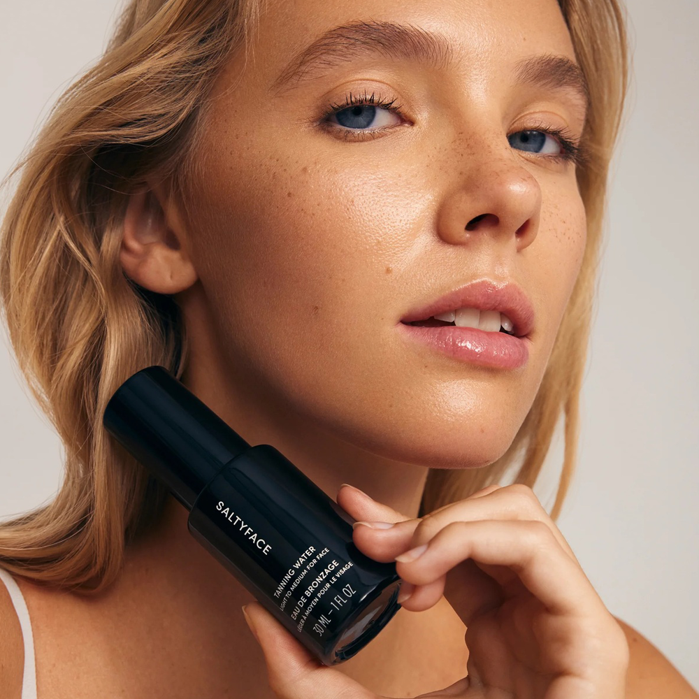 Woman holding a Saltyface product against a neutral background