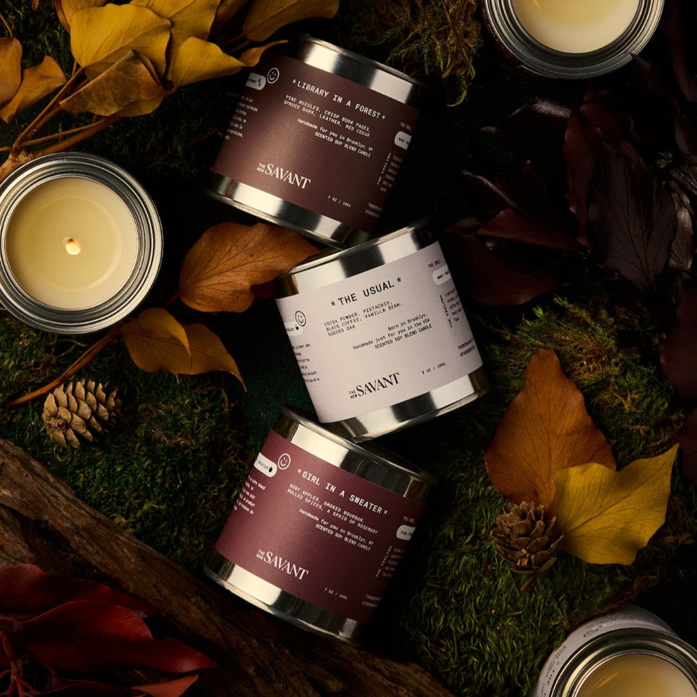 Scented candles and containers on a decorative surface with leaves and moss