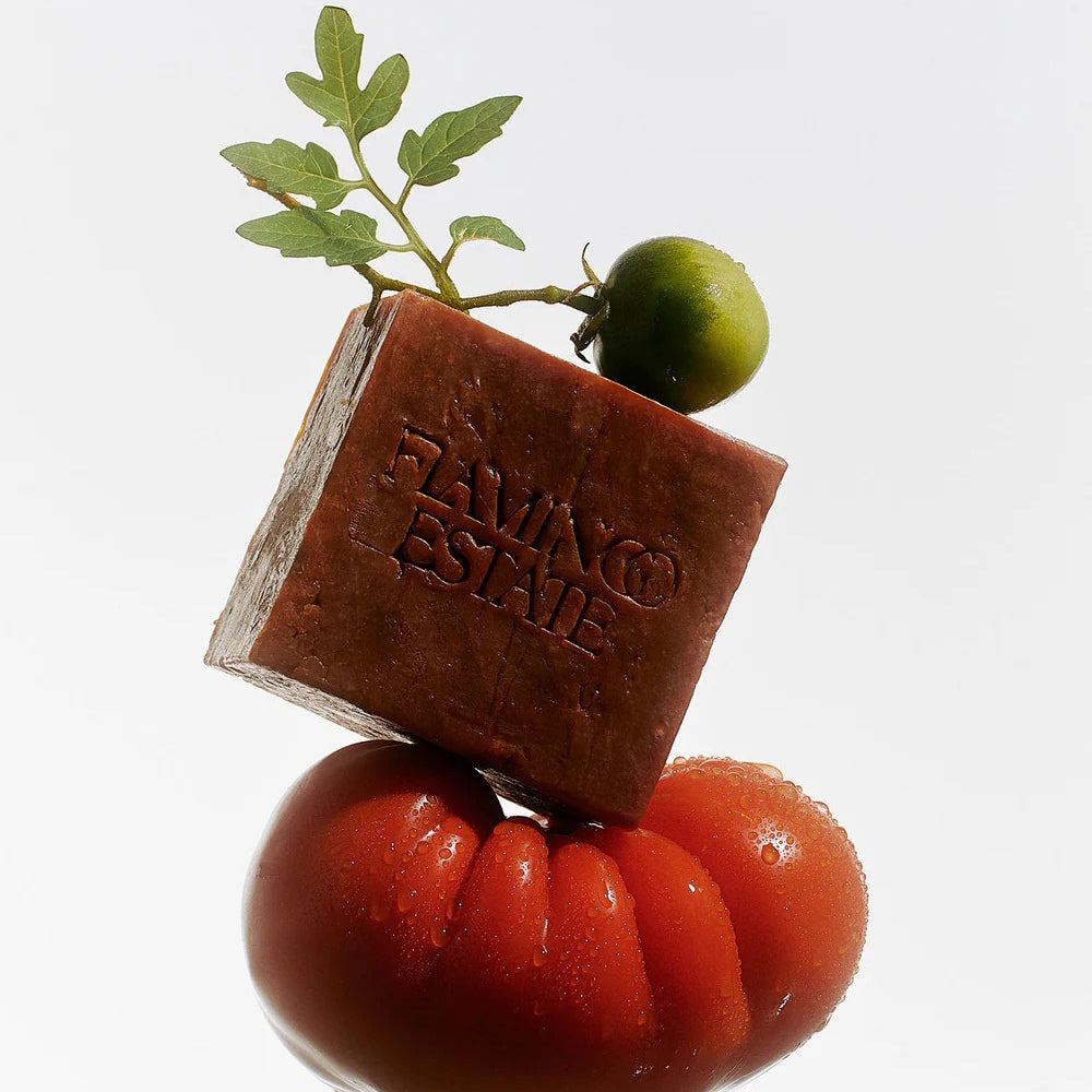 Bar of soap with 'Flamingo Estate' branding on a tomato with a green leaf.