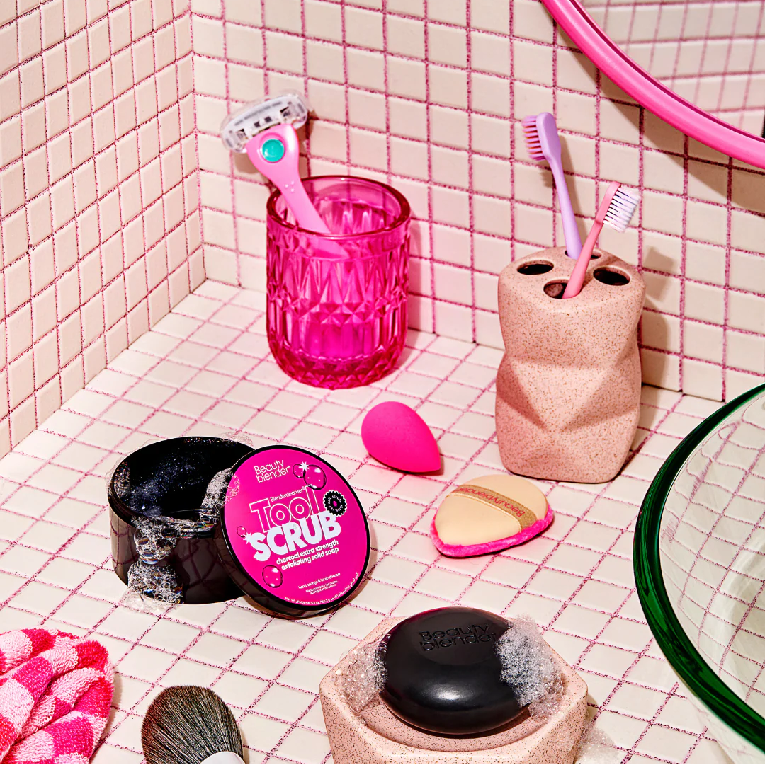 Bathroom scene with pink and black toiletries on a tiled wall.