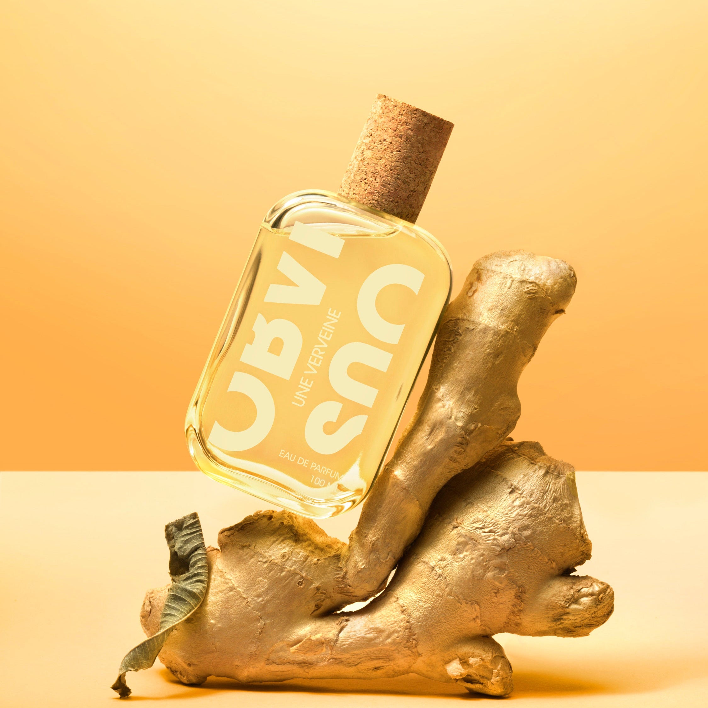 Bottle of perfume on a piece of ginger with a yellow gradient background
