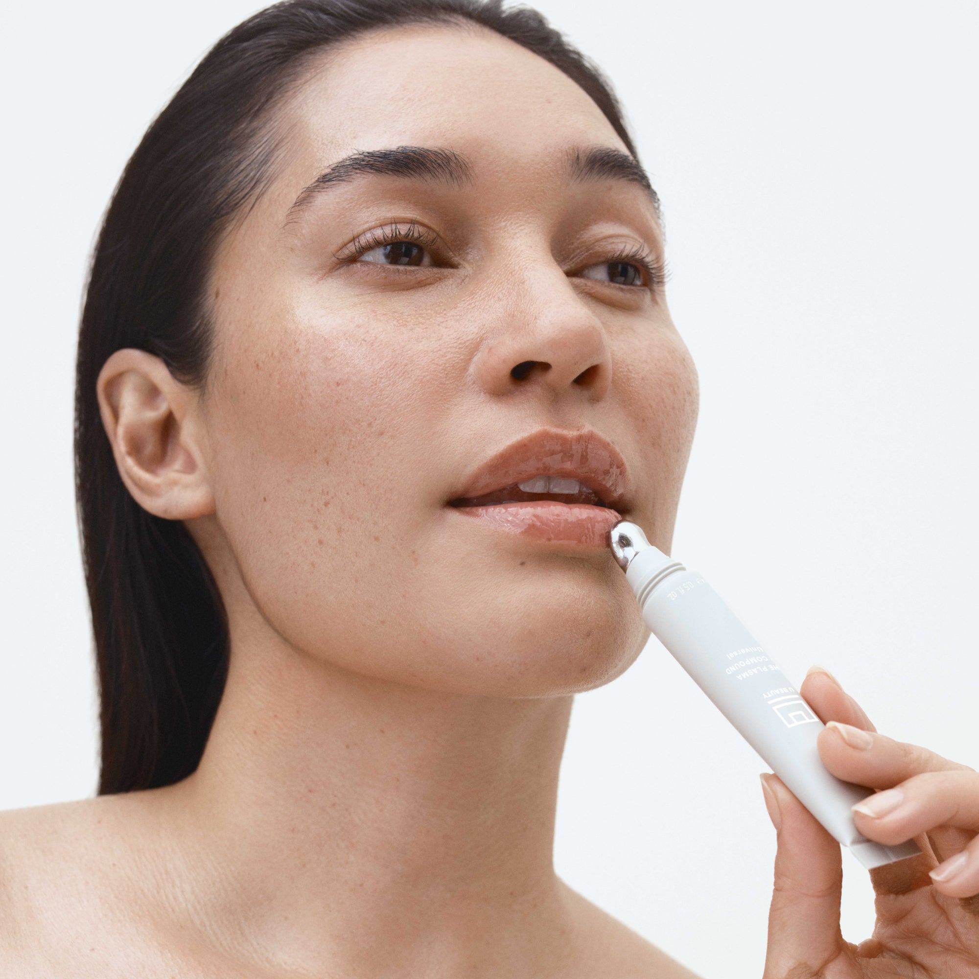 Woman applying lip product against a light background