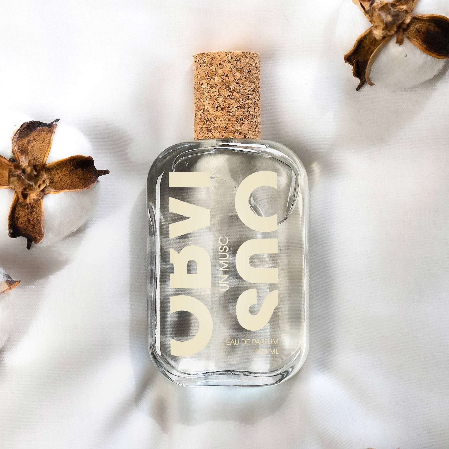 Perfume bottle with cork cap on a white background with dried flowers and cotton.