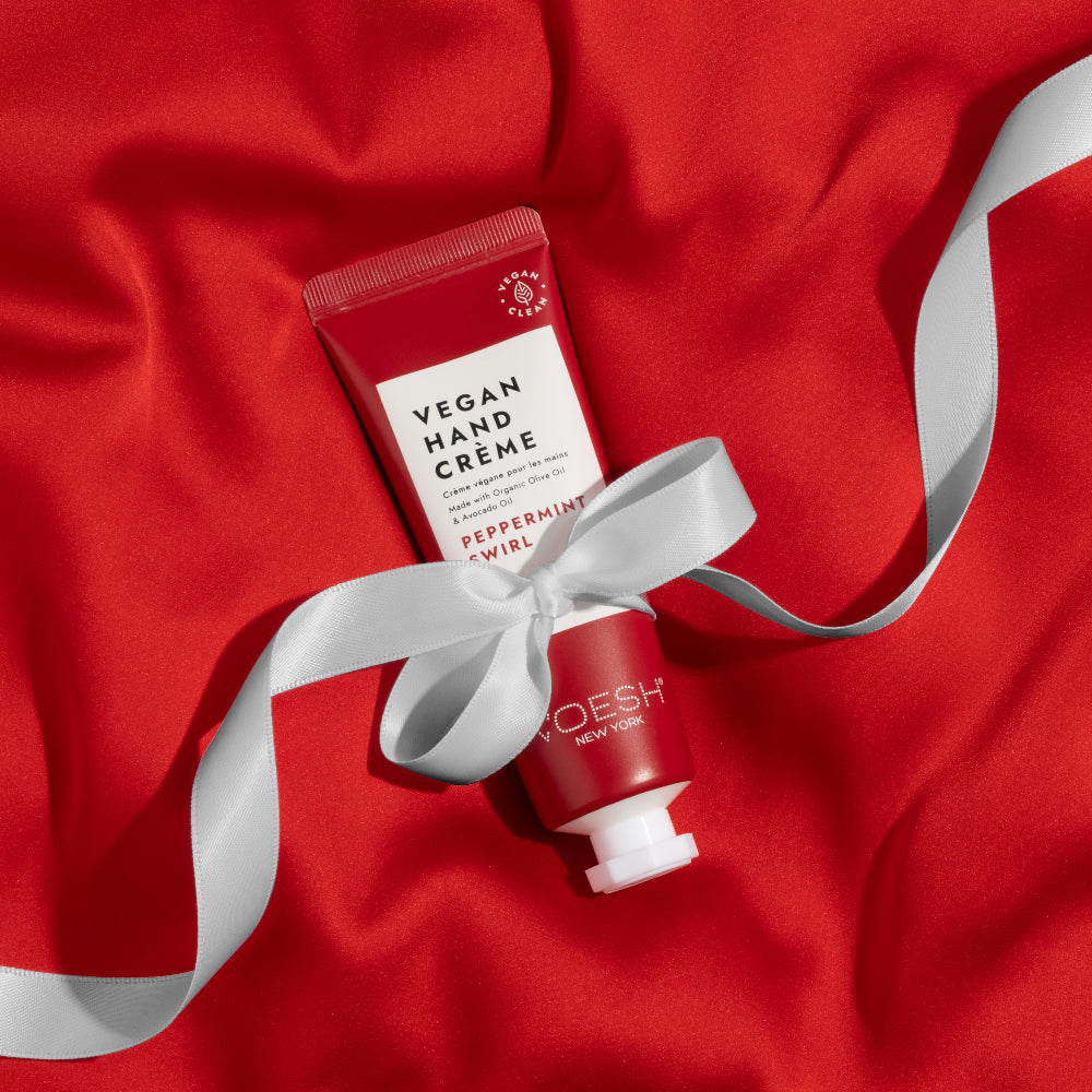 Red hand cream with a white ribbon on a red fabric background